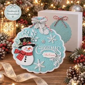 Personalised turquoise snowman Christmas card with layered white snowflakes and a matching gift box, handmade in the UK