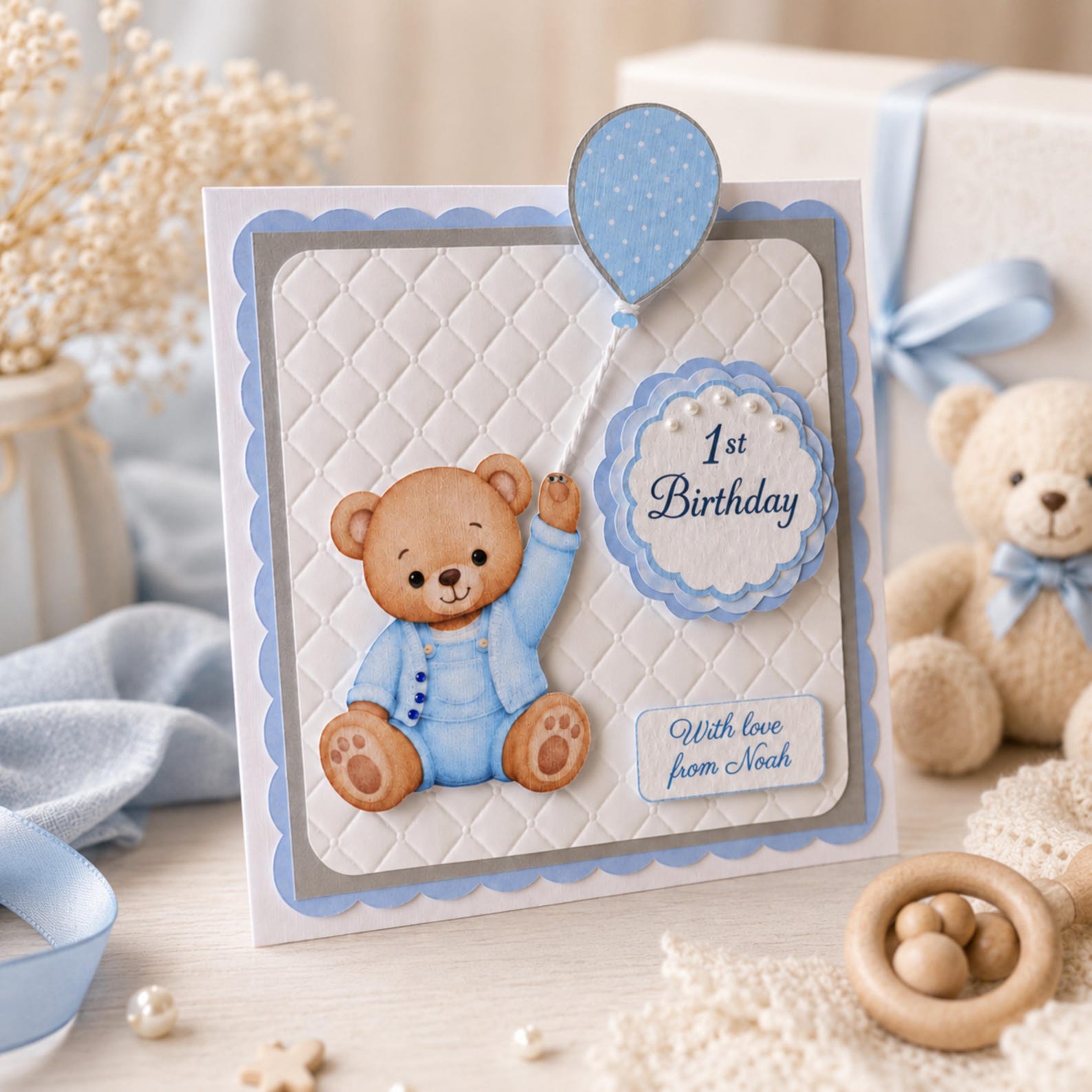 Close-up of personalised baby boy first birthday card with blue teddy bear details and faux pearls